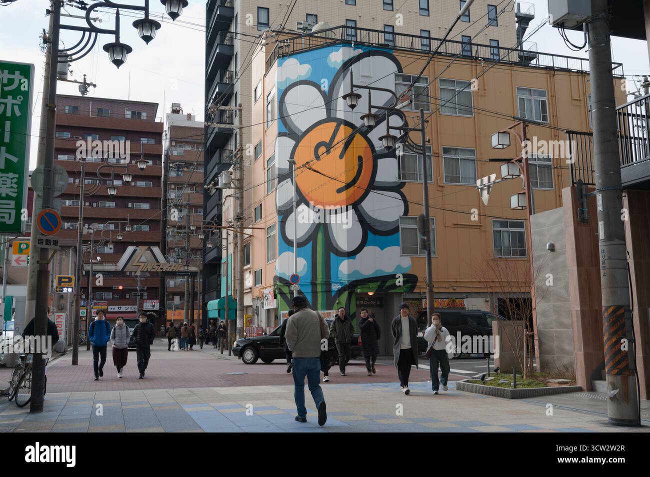 Un vivace murale di un fiore sorridente illumina una strada della città di Osaka Foto Stock