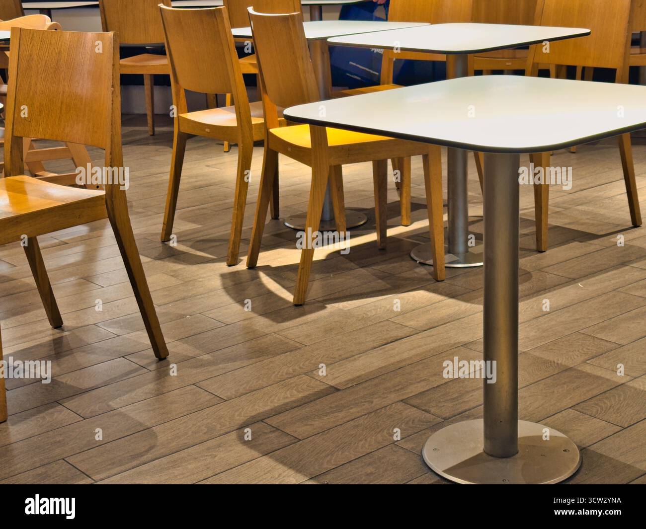 Moderno e vuoto, con sedie e tavoli in legno sul pavimento in parquet, accogliente disposizione dei posti a sedere del ristorante con luce calda e min. Contemporanei Foto Stock