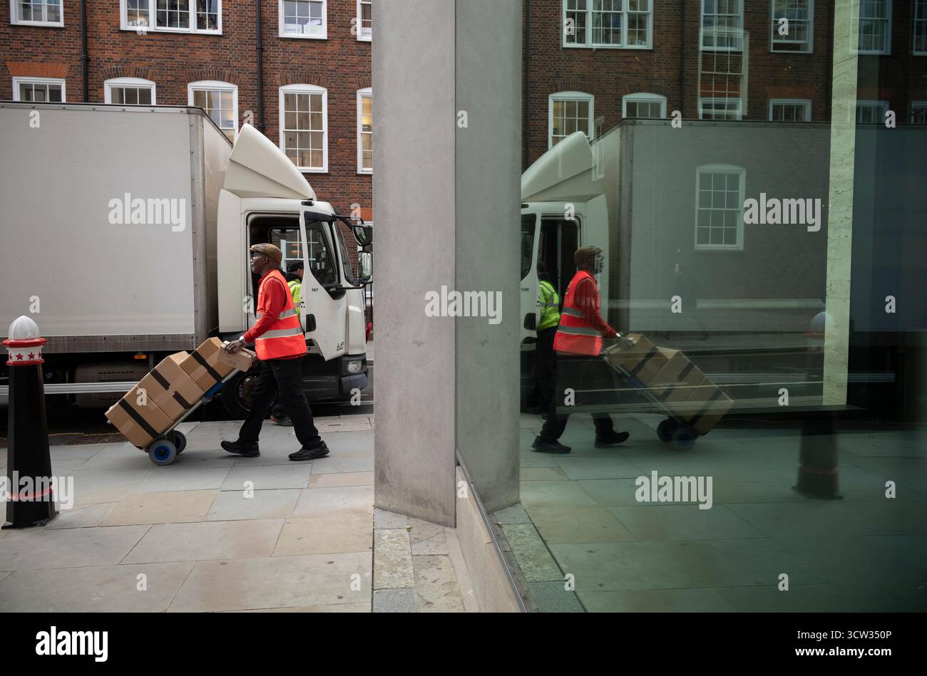 Un impiegato postale della Royal mail spinge un carrello di scatole lungo Chancery Lane, nel centro di Londra, Inghilterra, Regno Unito Foto Stock