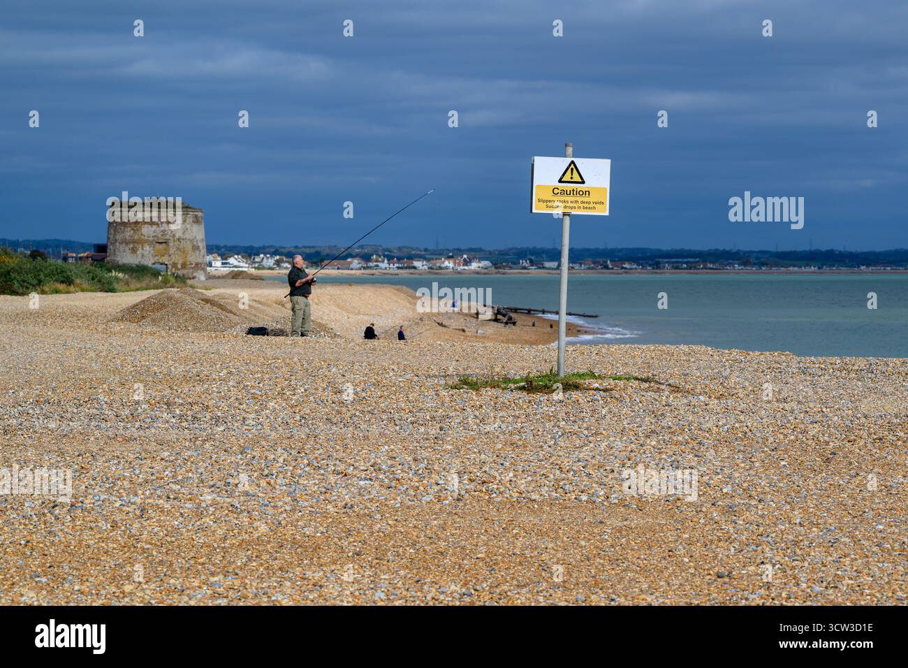Un uomo in pensione che pesca in mare dalla spiaggia di Eastbourne, Inghilterra Foto Stock
