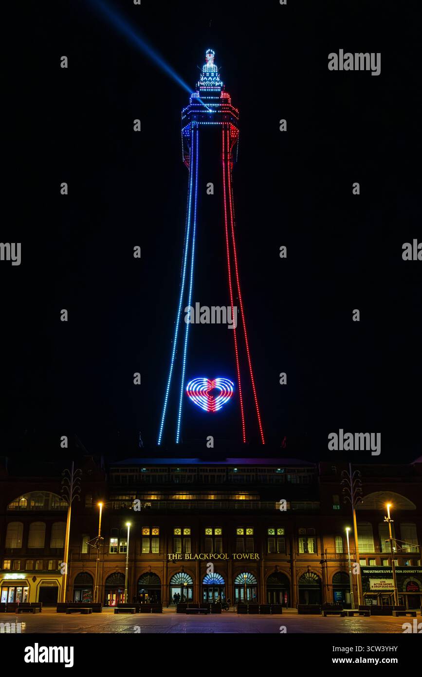 l'iconica torre di blackpool di notte illuminata in rosso e blu proietta un fascio di luce dalla parte superiore e mostra un luccicante simbolo a forma di cuore di union jack Foto Stock