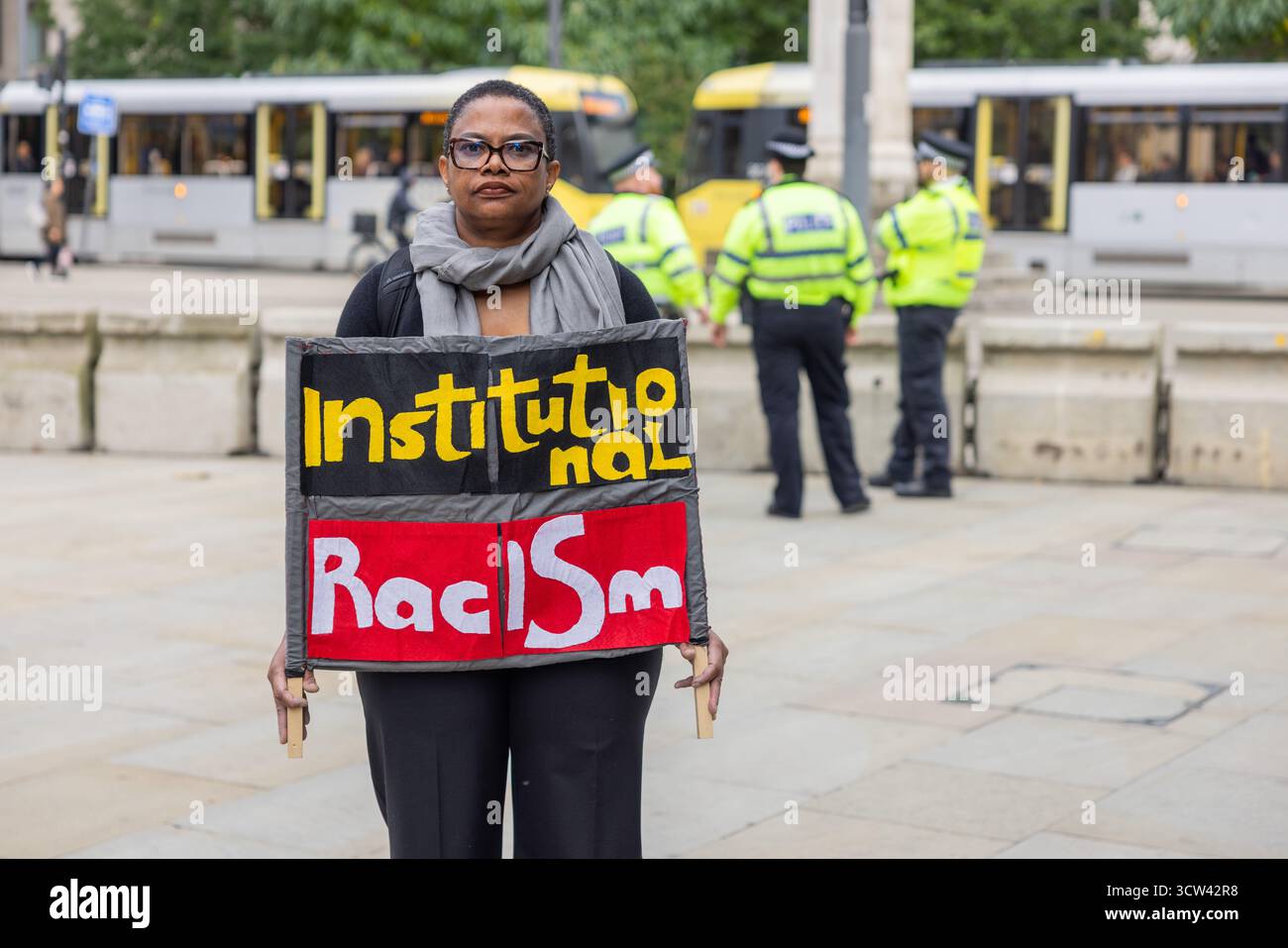 Manchester, Regno Unito. 7 OTTOBRE 2025. La persona si trova all'esterno della zona protetta con un cartello "Institutional Racism" il terzo giorno della Conferenza del Partito Conservatore tenutasi al Manchester Central Convention Center. Credito Milo Chandler/Alamy Live News Foto Stock