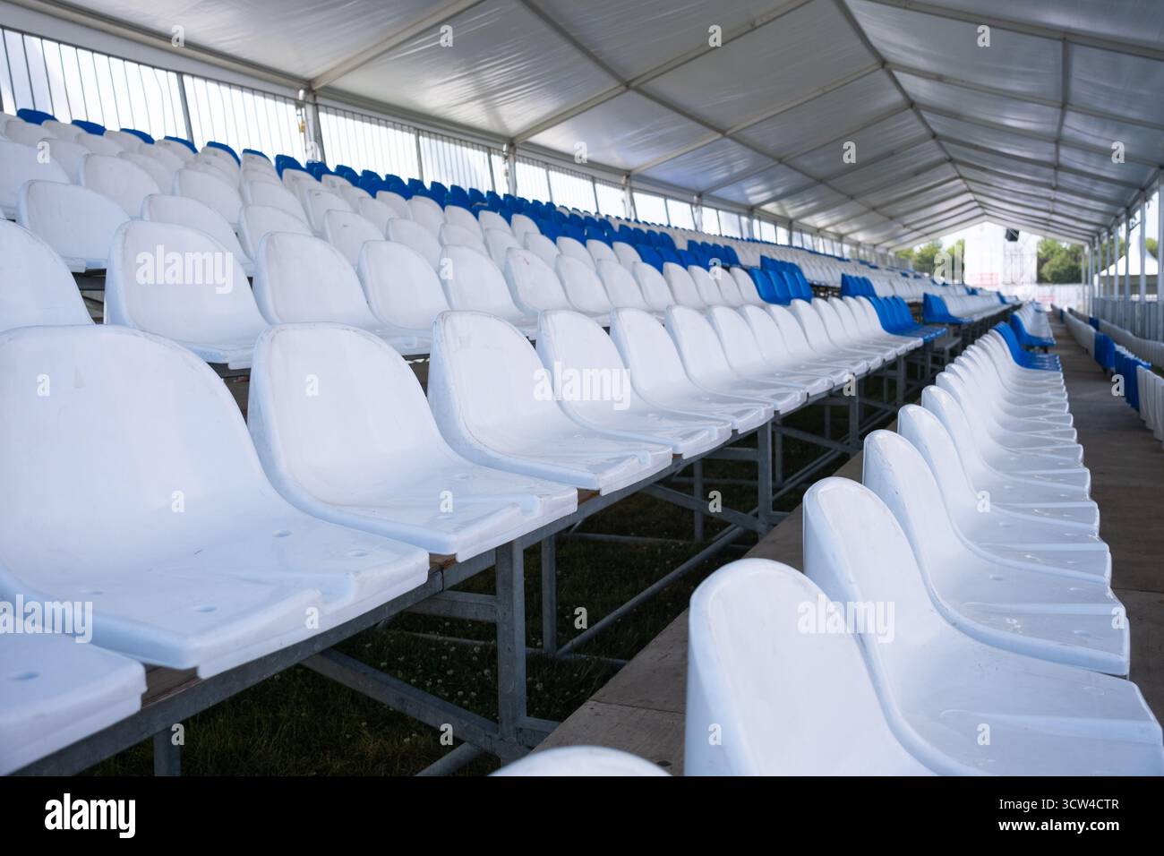 Posti vuoti bianchi di tribuna sullo stadio sportivo. Molti posti vuoti in plastica in fila in uno stadio all'aperto. Concetto di fan, sedie per il pubblico Foto Stock