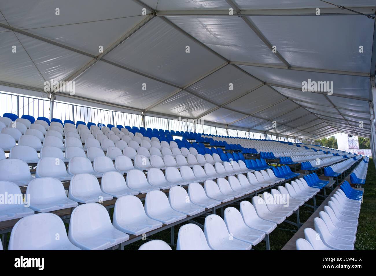 Posti vuoti bianchi di tribuna sullo stadio sportivo. Molti posti vuoti in plastica in fila in uno stadio all'aperto. Concetto di fan, sedie per il pubblico Foto Stock
