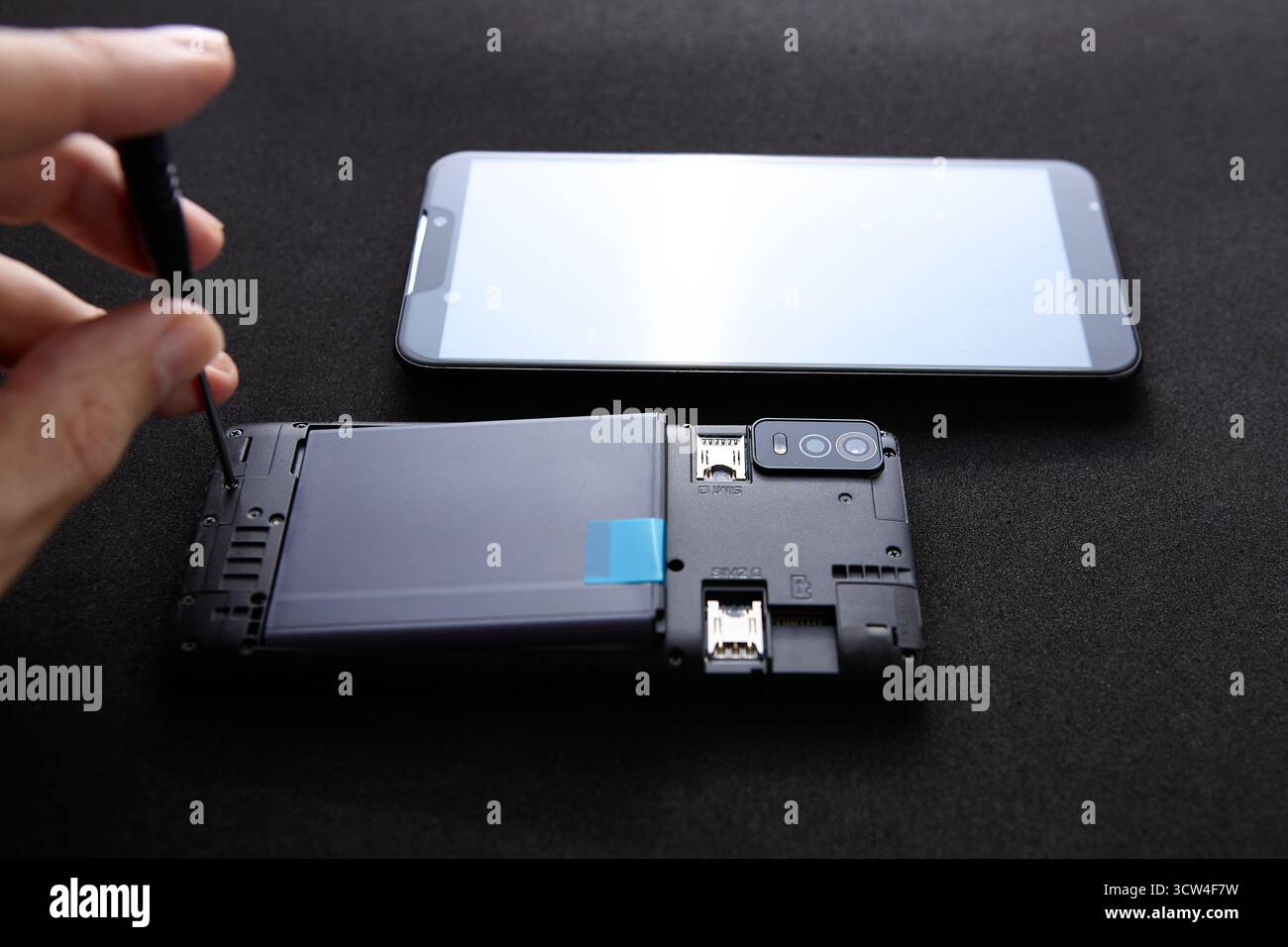 Uno smartphone si è aperto con un display separato accanto su sfondo scuro. Il concetto rappresenta la sostituzione dello schermo del telefono e il riparatore professionale Foto Stock