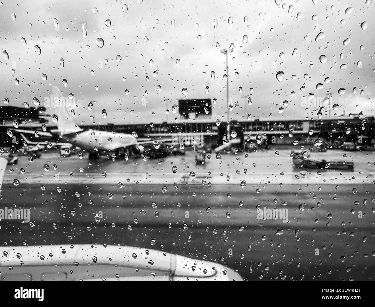 Vista dell'aeroporto dalla finestra dell'aereo con gocce di pioggia Foto Stock