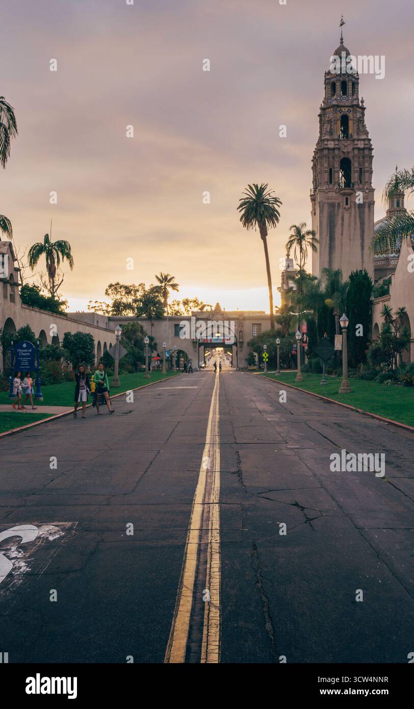 I visitatori passeggiano nel Balboa Park mentre il sole tramonta, proiettando un caldo bagliore sugli edifici storici e sui lussureggianti paesaggi, creando un'atmosfera tranquilla. Foto Stock