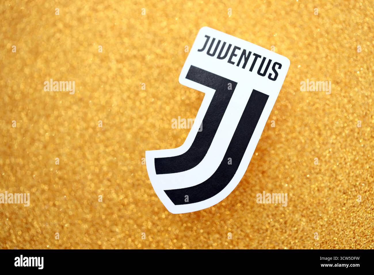 KIEV, UCRAINA - 23 FEBBRAIO 2025 il distintivo della squadra di calcio della Juventus FC si trova su uno sfondo giallo dorato glitter Foto Stock