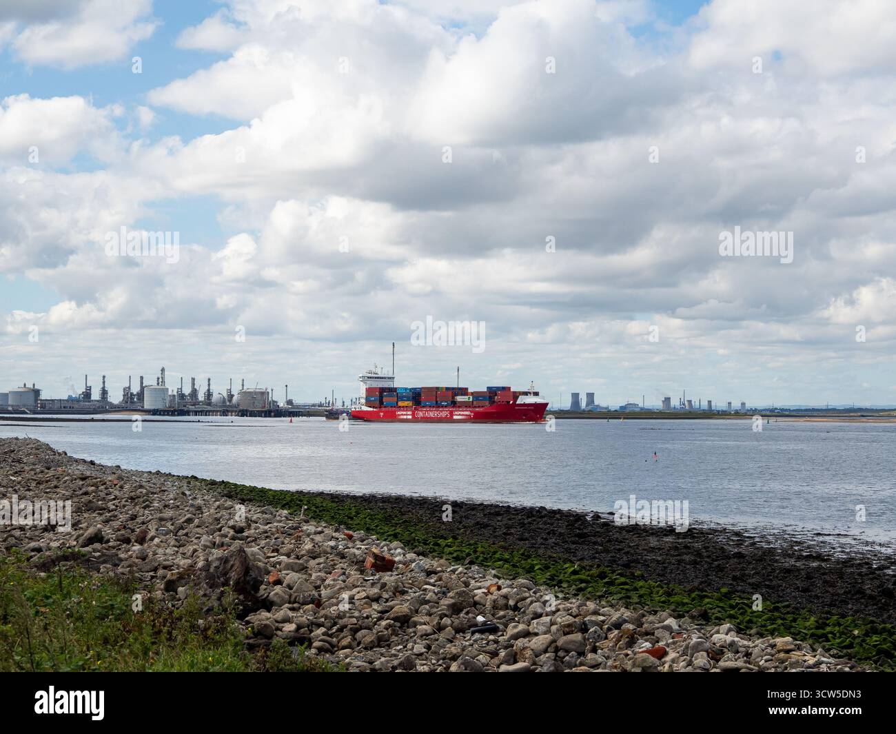 Nave portacontainer rossa sul fiume Tees passando per le opere industriali sull'estuario di Tees Foto Stock