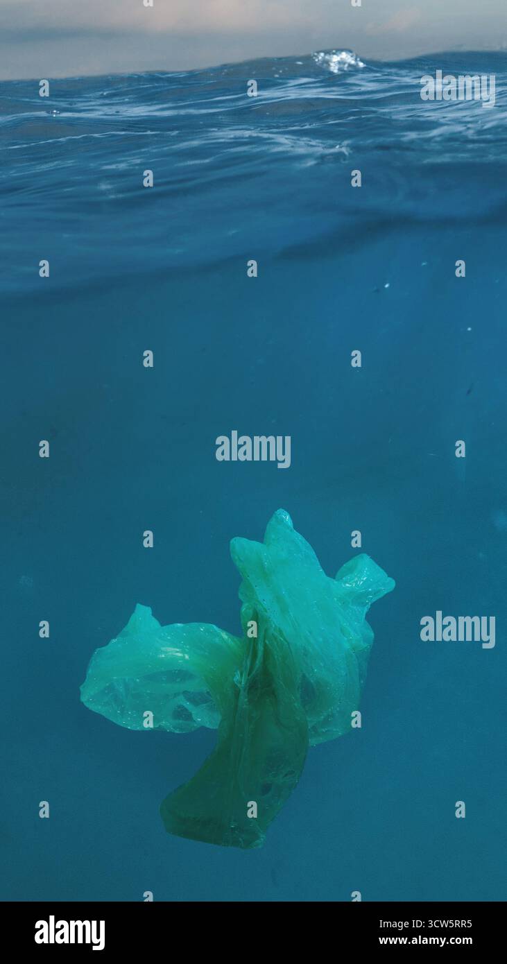 Detriti di plastica che galleggiano nell'acqua pulita dell'oceano sotto la luce del sole Foto Stock