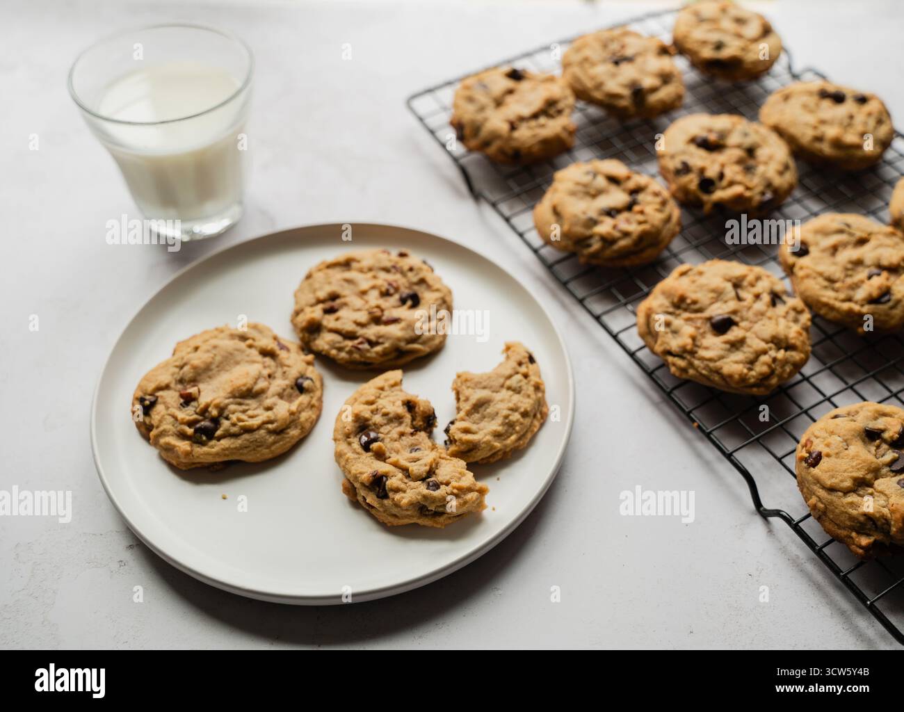 Biscotti al cioccolato appena sfornati con latte su sfondo bianco. Foto Stock