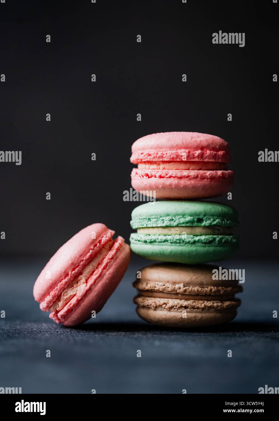 Primo piano di biscotti di macaron assortiti su sfondo nero. Foto Stock
