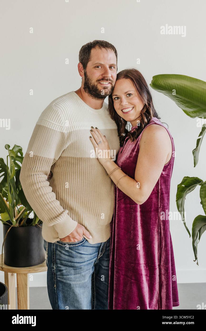 Marito e moglie si abbracciano in studio con piante Foto Stock