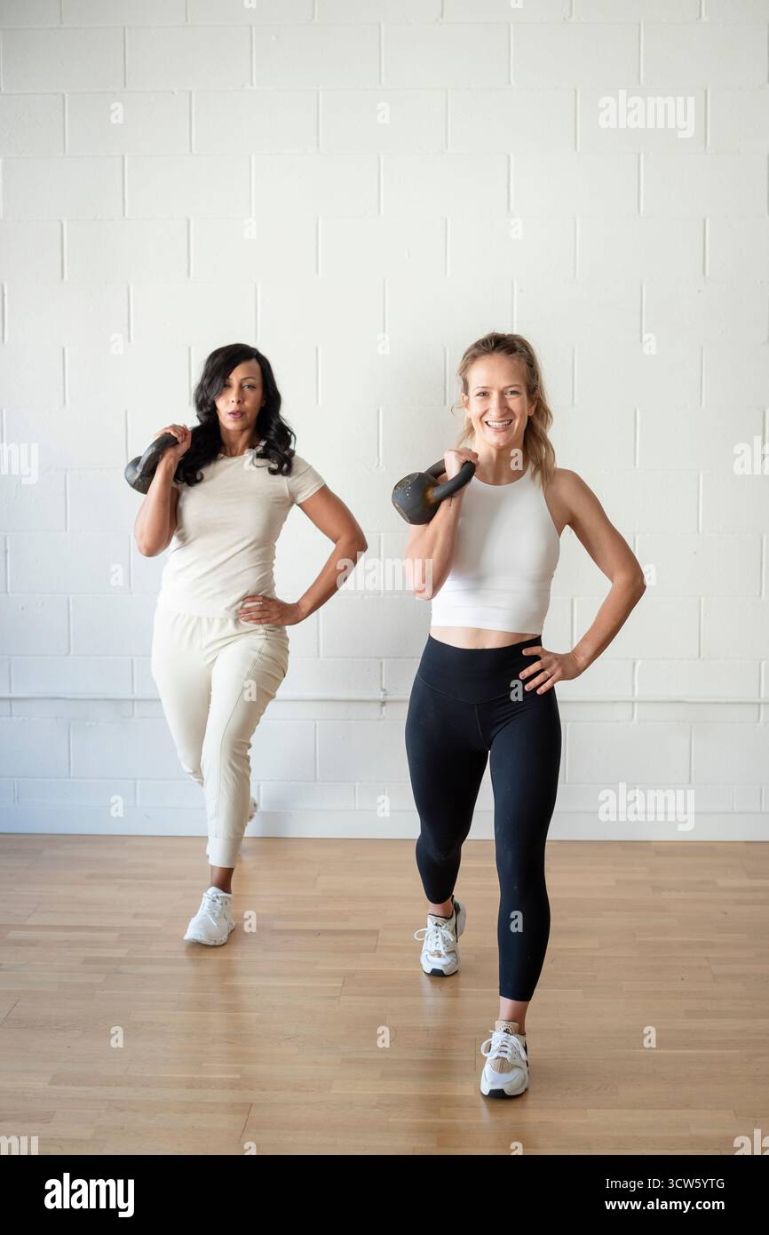 Donne forti che fanno affondi di kettlebell a San Francisco Foto Stock