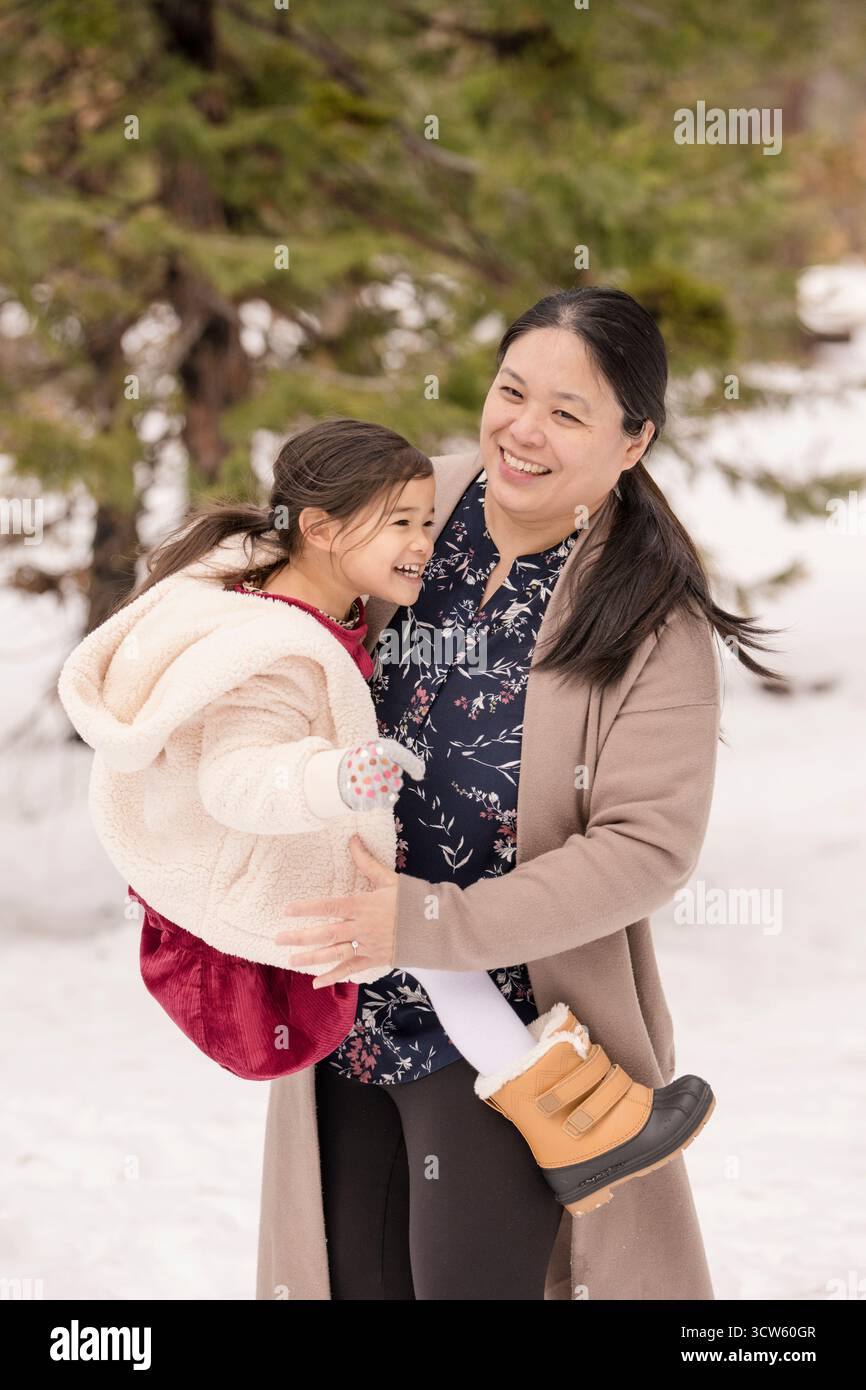 Madre e figlia condividono un momento di gioia nella foresta innevata di Tahoe Foto Stock
