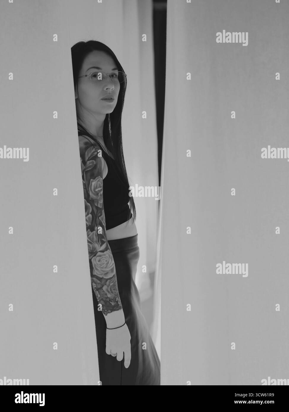 Donna con tatuaggi in piedi tra un tessuto drappeggiato Foto Stock