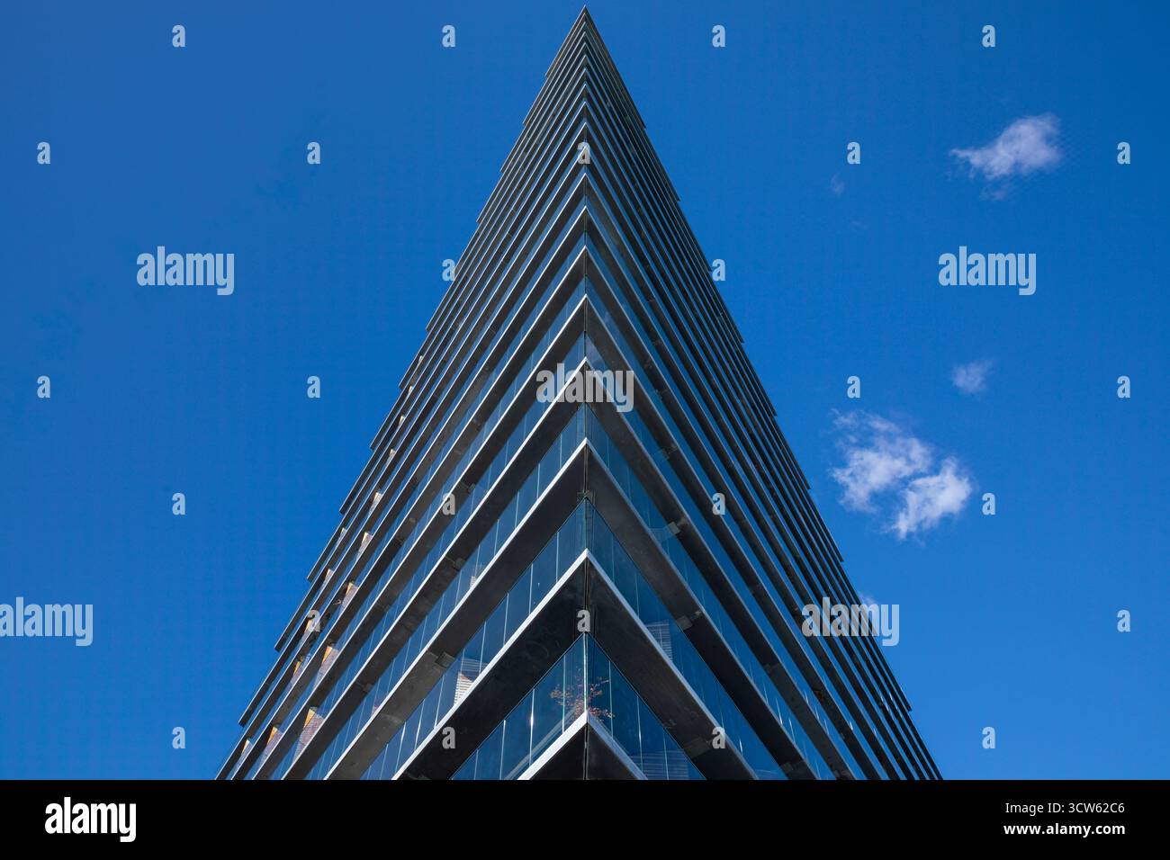 Vista ad angolo basso dell'edificio con angoli netti contro il cielo blu con piccole nuvole soffici Foto Stock