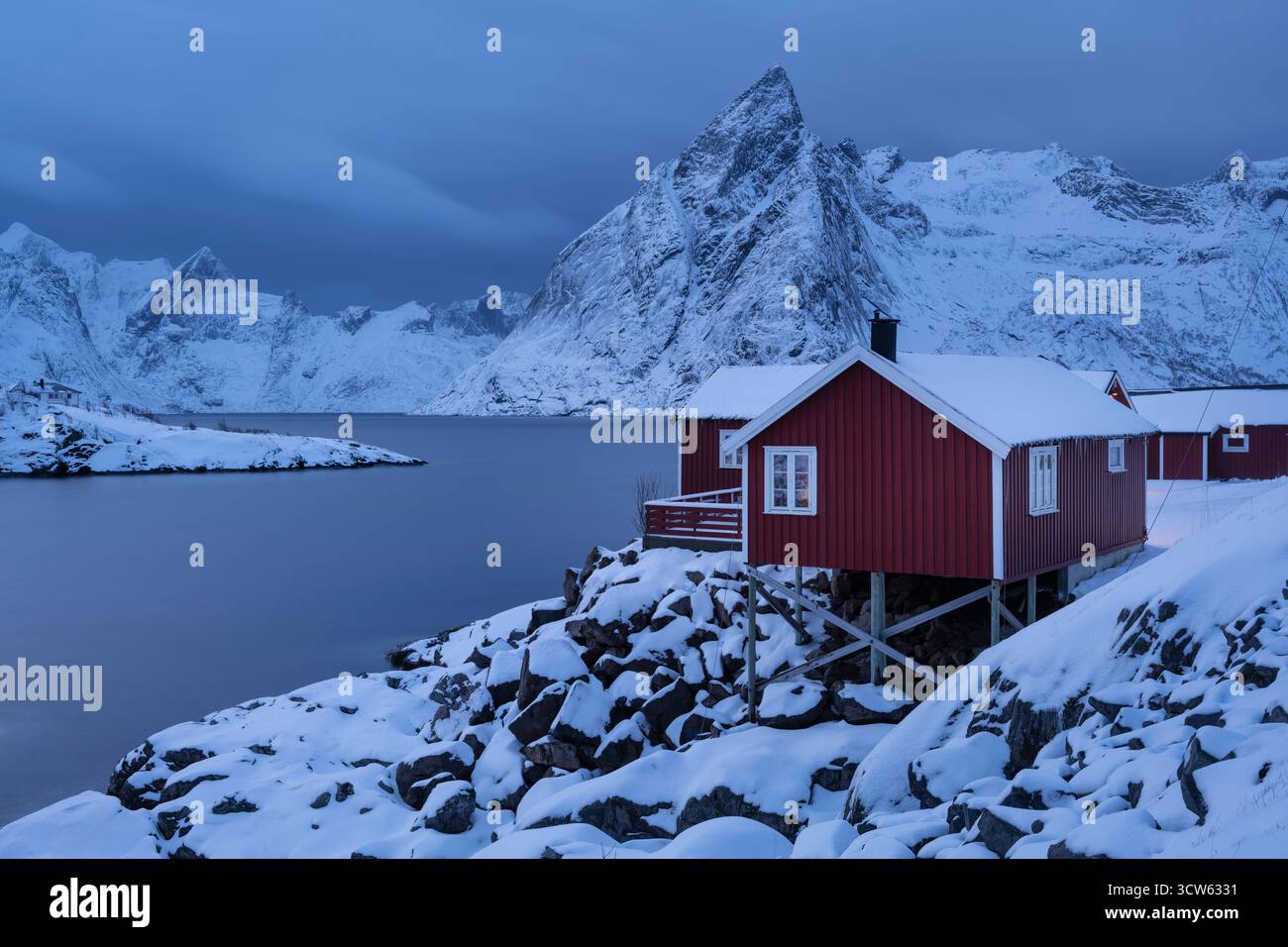 Monte Olstind sulle cabine rosse di Rorbu, isole Lofoten, Norvegia Foto Stock