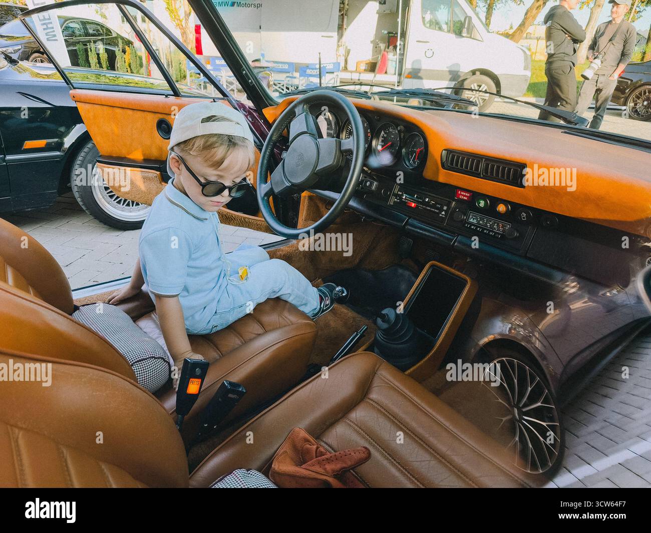 Vilnius, Lituania - 2025-09-20 - elegante ragazzo con occhiali da sole seduto al volante di un interno Porsche vintage Foto Stock