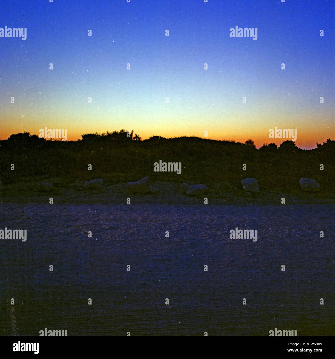 Crepuscolare con rocce e una strada in primo piano, catturata su pellicola di formato medio e scansionata con artefatti analogici e digitali visibili Foto Stock