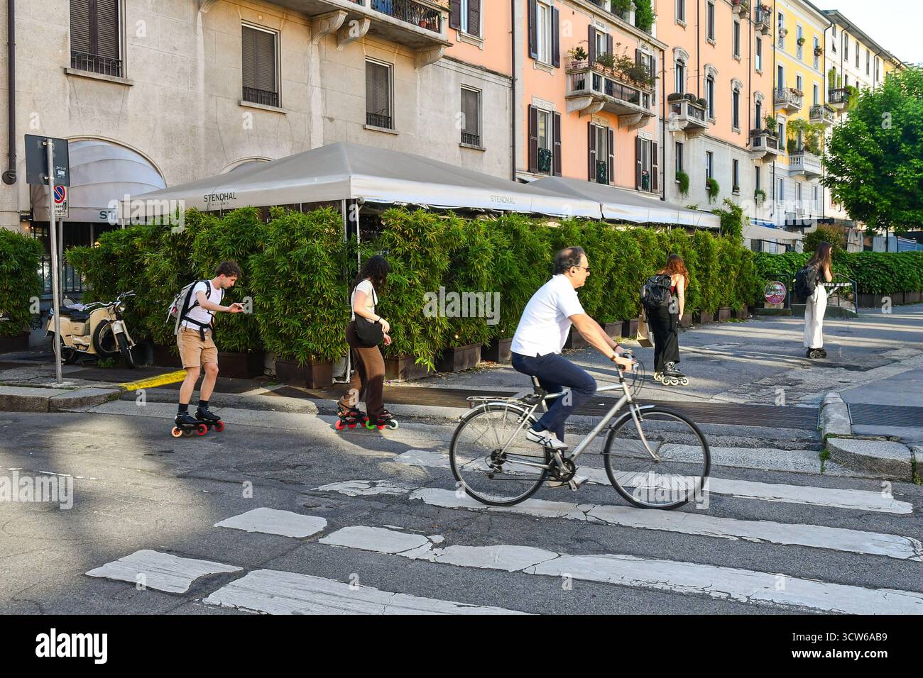 Vista su via San Marco con un piccolo gruppo di giovani su pattini e un uomo in bicicletta, in primavera, Milano, Lombardia, Italia Foto Stock