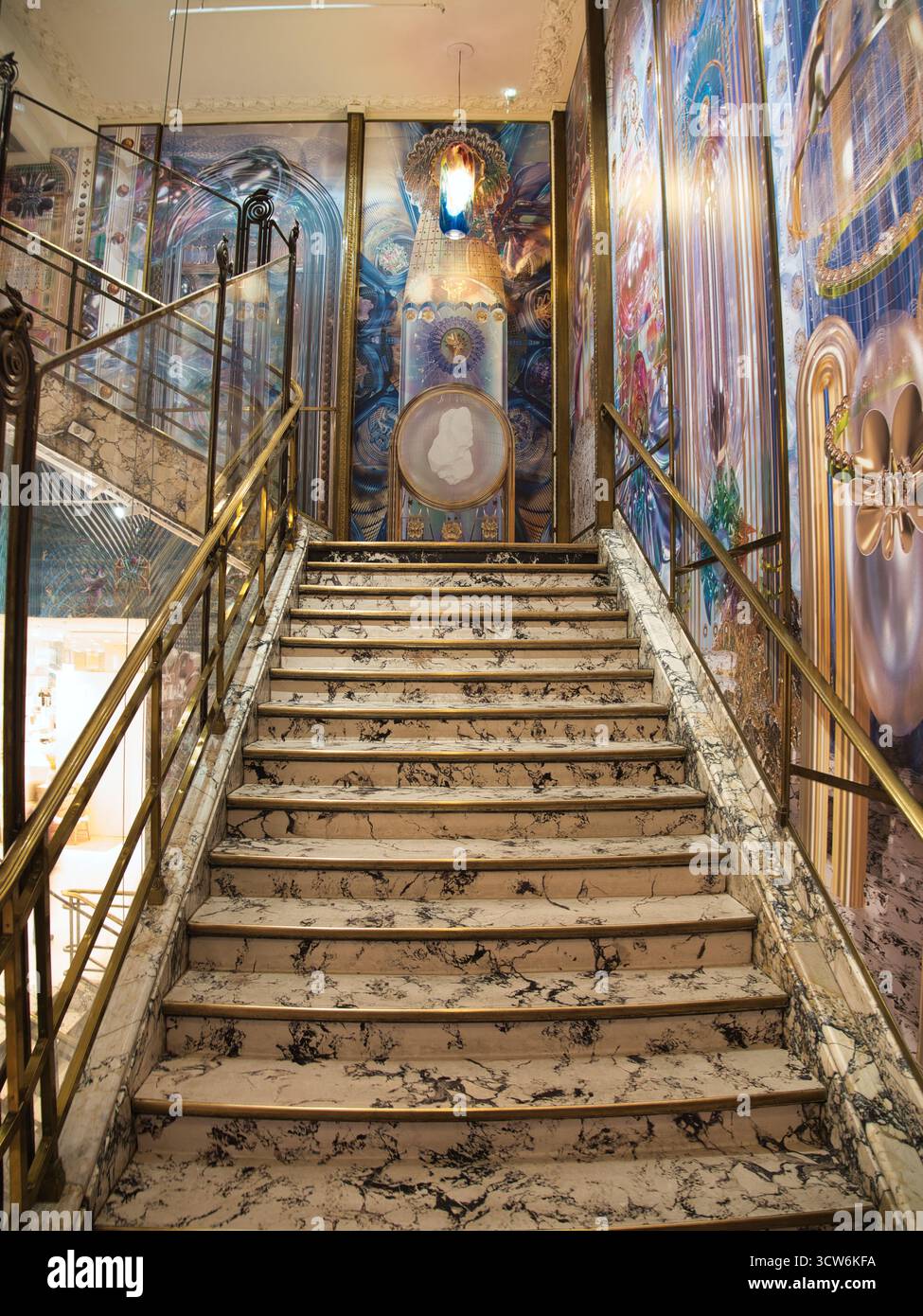 Sfarzosa scala in marmo con murale artistico - grande scala interna con gradini in marmo bianco e nero lucido, ringhiere in ottone dorato e colorfu Foto Stock