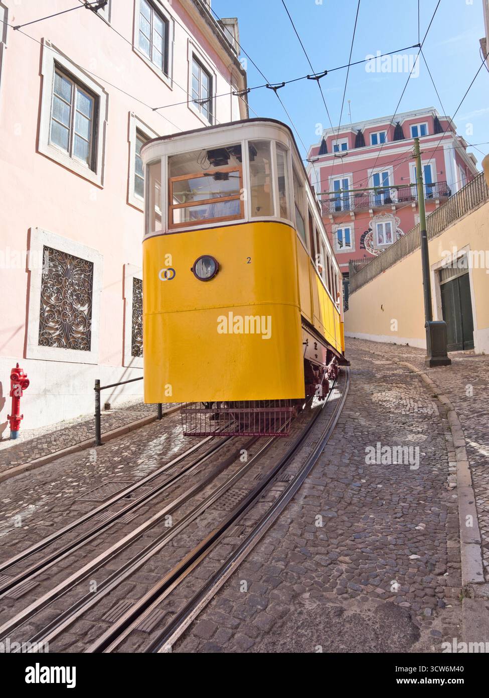 Funicolare di Glória sulla ripida collina di Lisbona - tram d'epoca giallo Elevador da Glória che sale sulla ripida collina di Bairro alto di Lisbona su una strada acciottolata, accanto Foto Stock