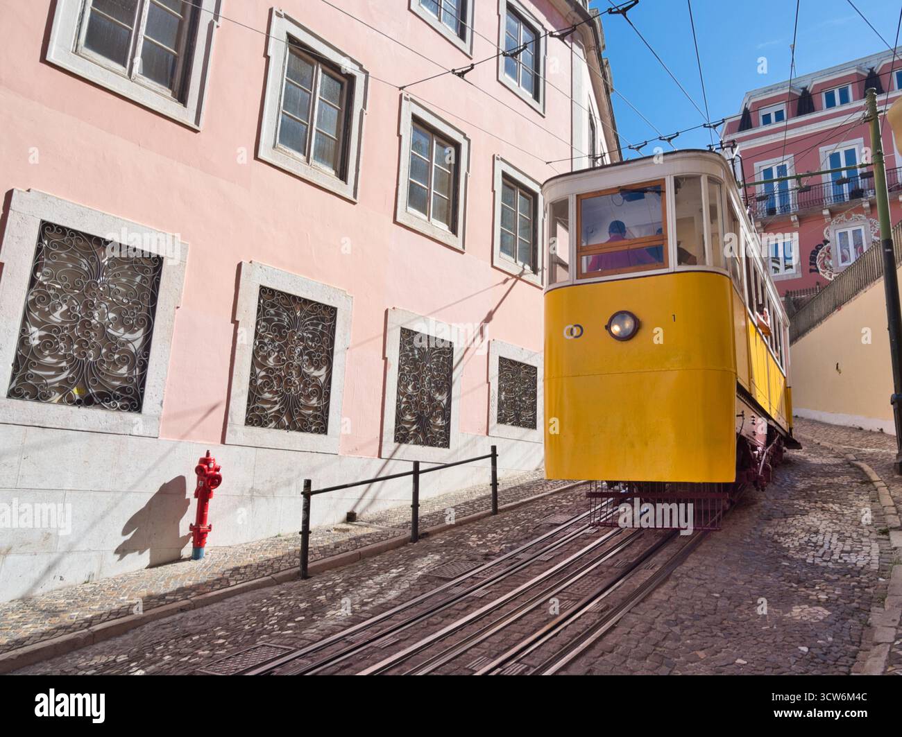 Funicolare di Glória sulla ripida collina di Lisbona - tram d'epoca giallo Elevador da Glória che sale sulla ripida collina di Bairro alto di Lisbona su una strada acciottolata, accanto Foto Stock