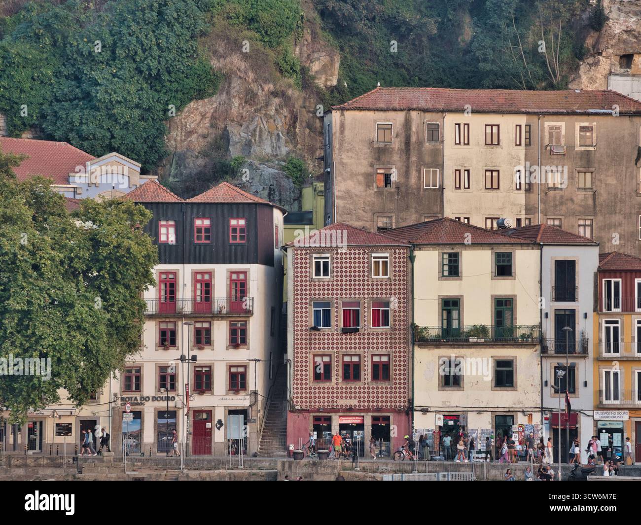 Edifici storici sul lungofiume e scogliera a Porto, Portogallo - fila di case tradizionali e colorate del quartiere di Ribeira con tetti di tegole rosse annidate Foto Stock
