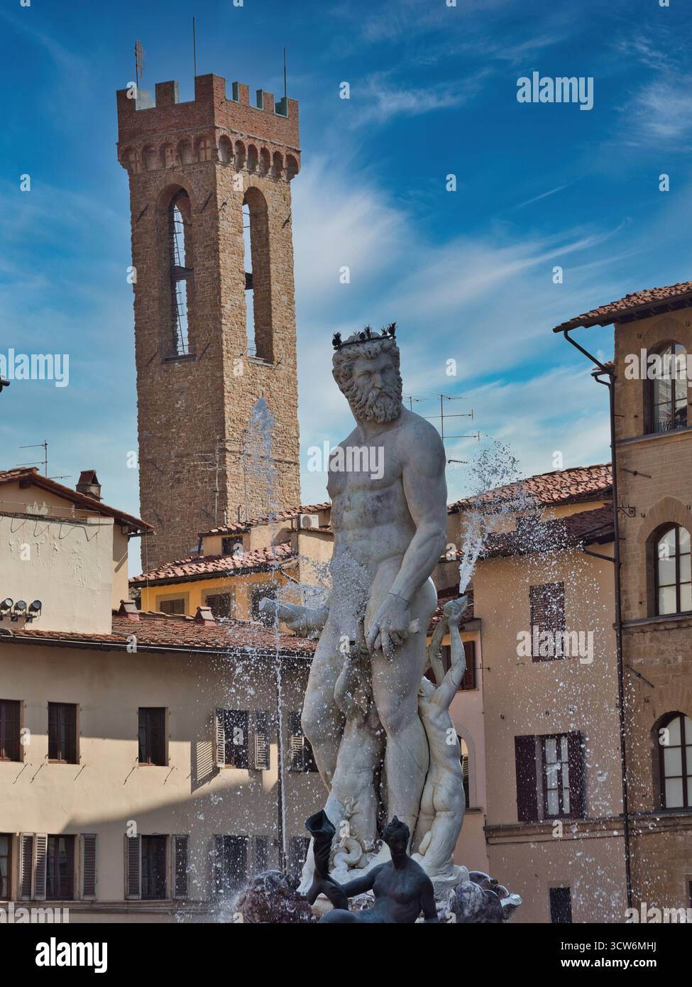 Fontana del Nettuno e Torre del Bargello a Firenze - primo piano verticale della statua in marmo bianco del Nettuno con spruzzi d'acqua, adagiata contro la storica S Foto Stock