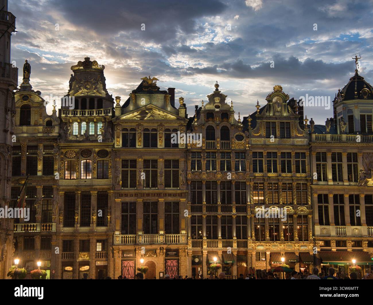 Brussels Grand Place Guildhalls at Dusk - sale di gildhall ornate sulla Grand Place di Bruxelles, Belgio, illuminate al tramonto sotto un cielo drammatico e nuvoloso. Foto Stock