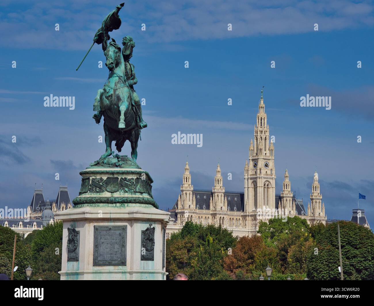 Statua dell'arciduca Carlo e Municipio di Vienna - monumento equestre in bronzo con il Rathaus neogotico, un iconico punto di riferimento politico, incorniciato da alberi A. Foto Stock