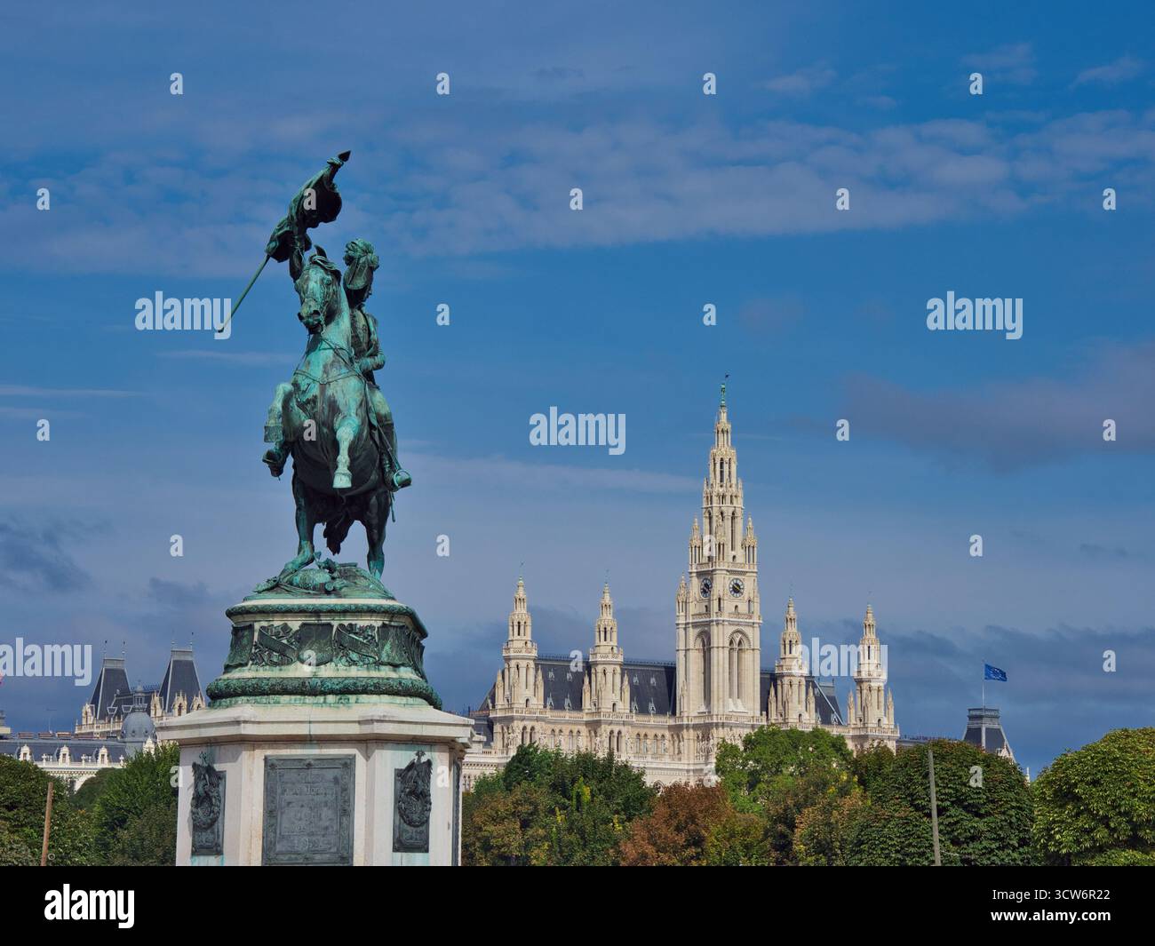 Statua dell'arciduca Carlo e Municipio di Vienna - monumento equestre in bronzo con il Rathaus neogotico, un iconico punto di riferimento politico, incorniciato da alberi A. Foto Stock