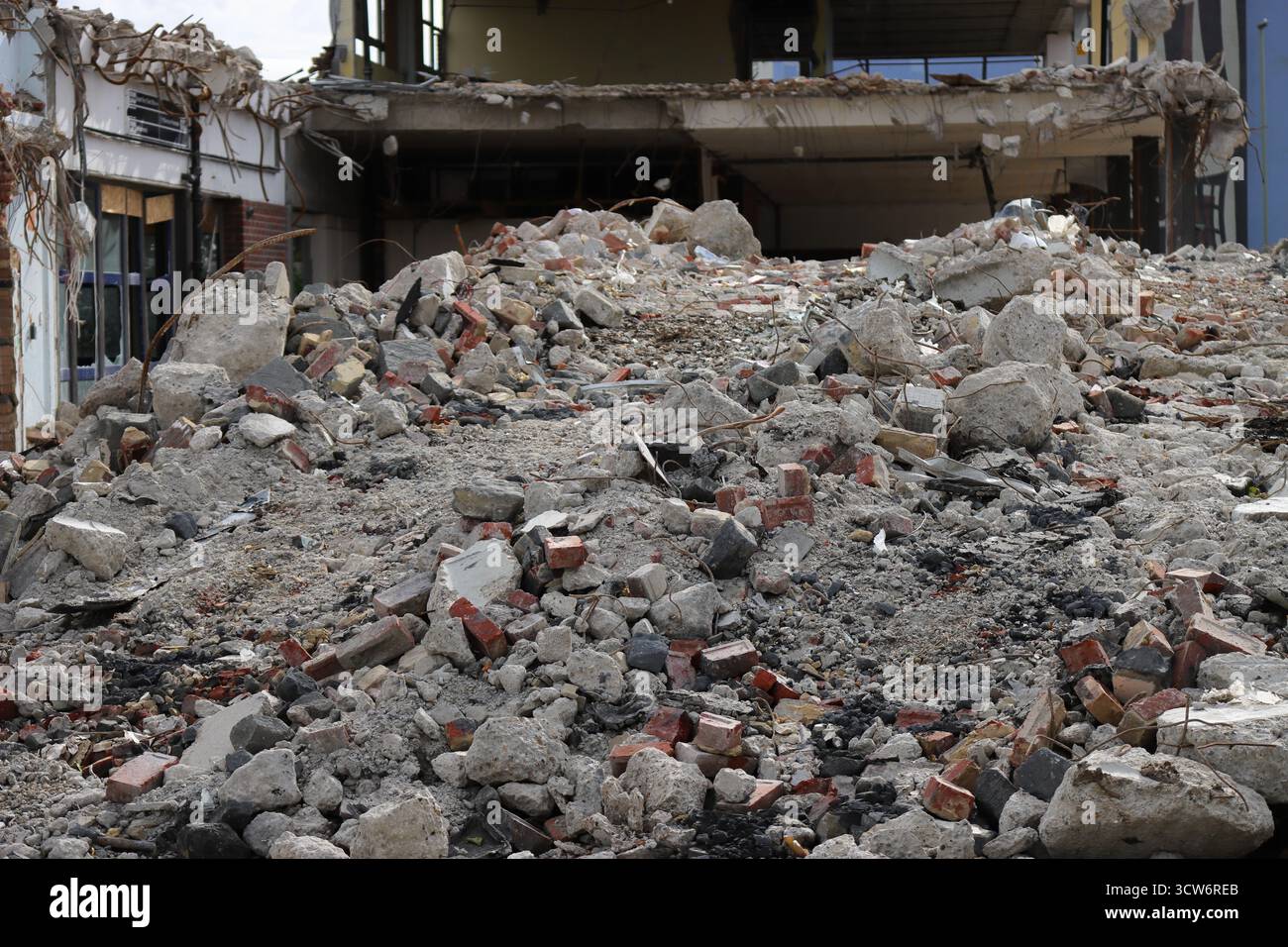 Demolizione in corso dell'ex stazione degli autobus di Gosport, Hampshire, Inghilterra. Un mucchio di macerie (mattoni, cemento e materiali fratturati) fuoriesce in primo piano di un edificio parzialmente demolito. Elementi strutturali esposti e pareti mancanti suggeriscono una decostruzione attiva. La scena è dura e transitoria, catturando il momento grezzo prima che il rinnovamento inizi nel tessuto urbano in evoluzione di Gosport. Foto Stock