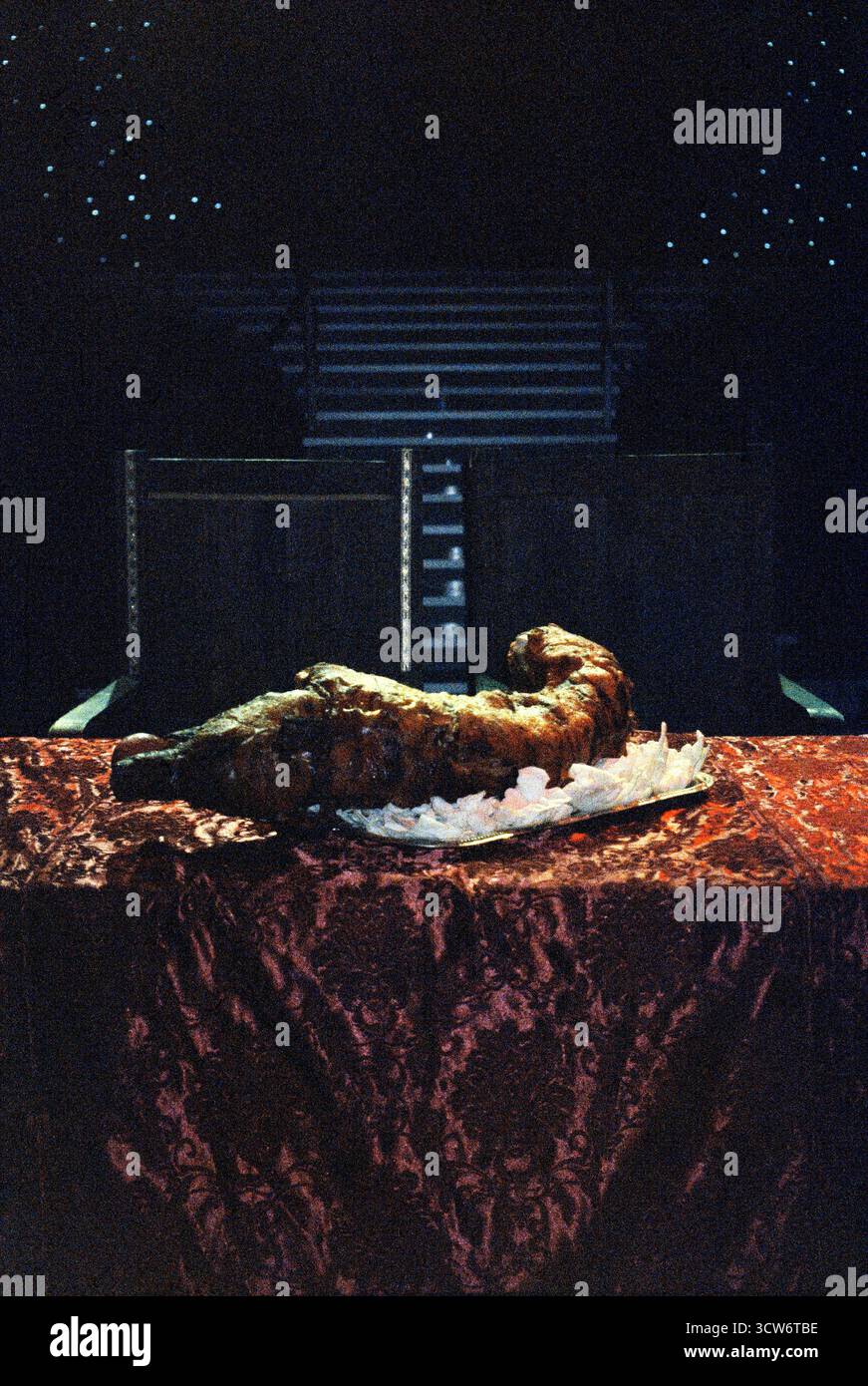 Maiale arrosto su un tavolo decorato in uno studio TV, illuminato da dietro. Texture contrastate e luci teatrali incorniciano una festa in scena. Foto Stock
