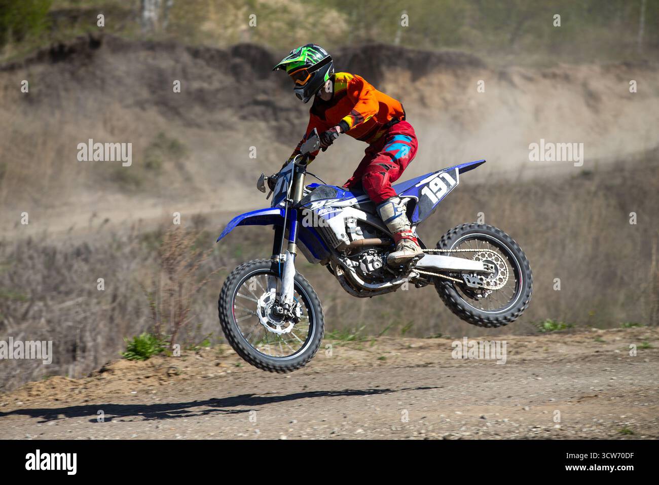Pilota di motocross che esegue il salto su una collina Foto Stock