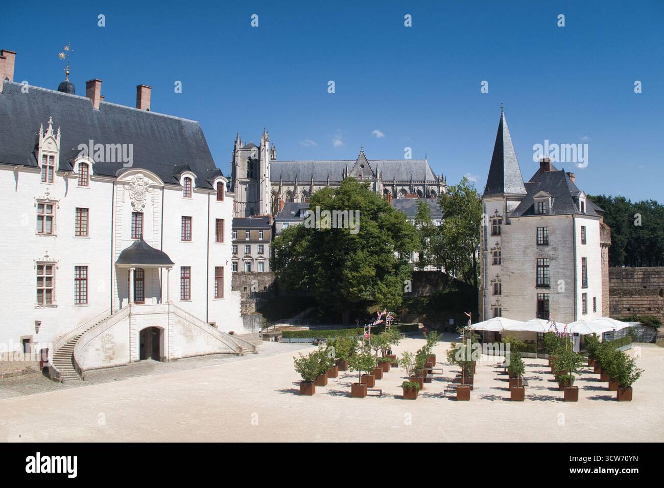 Cortile del castello e cattedrale gotica - Vista da un cortile del castello francese che mostra facciate bianche rinascimentali, una torretta scura e un massiccio edificio gotico Foto Stock