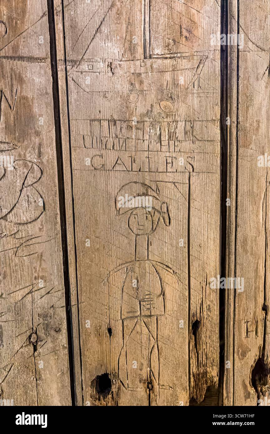 Scultura storica su un'antica porta di legno che mostra un graffito sospeso, forse delle truppe Foto Stock