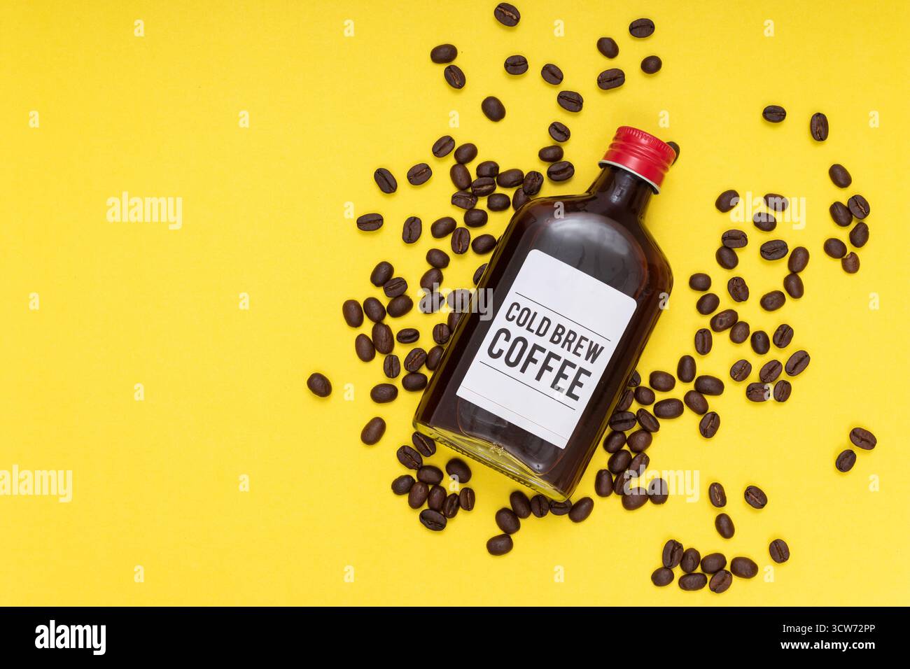 bottiglia di caffè freddo con chicchi di caffè, sfondo giallo, layout piatto Foto Stock