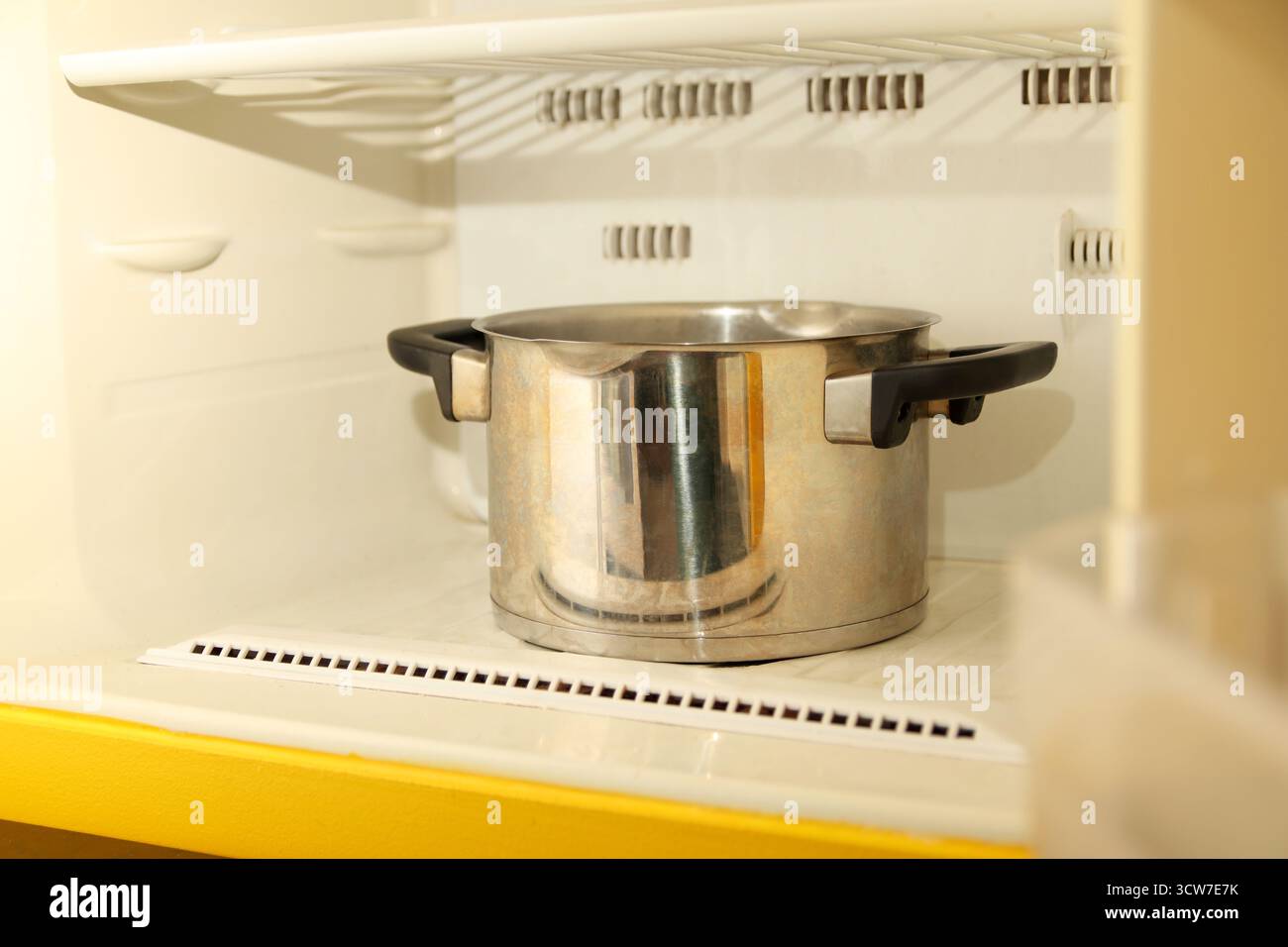 un congelatore o un frigorifero congelato con strati di ghiaccio spessi, con una pentola di acqua bollente all'interno per sciogliere il gelo. Foto Stock