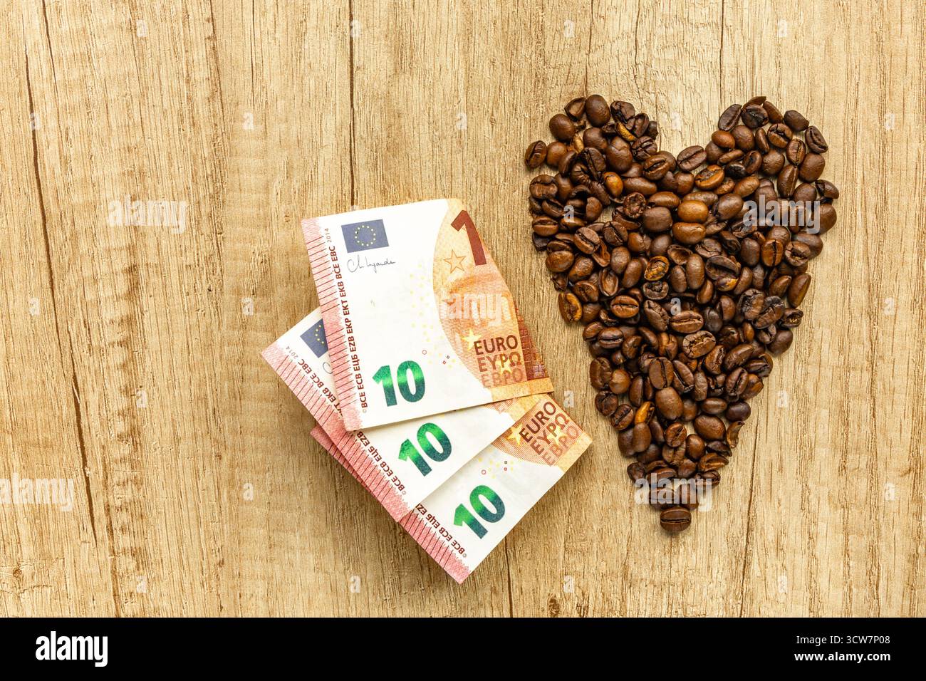 Vista dall'alto di una tazza di caffè con chicchi di caffè a forma di cuore su un tavolo di legno. Simbolo dell'amore per il caffè, la colazione e le accoglienti vibrazioni mattutine. Foto Stock