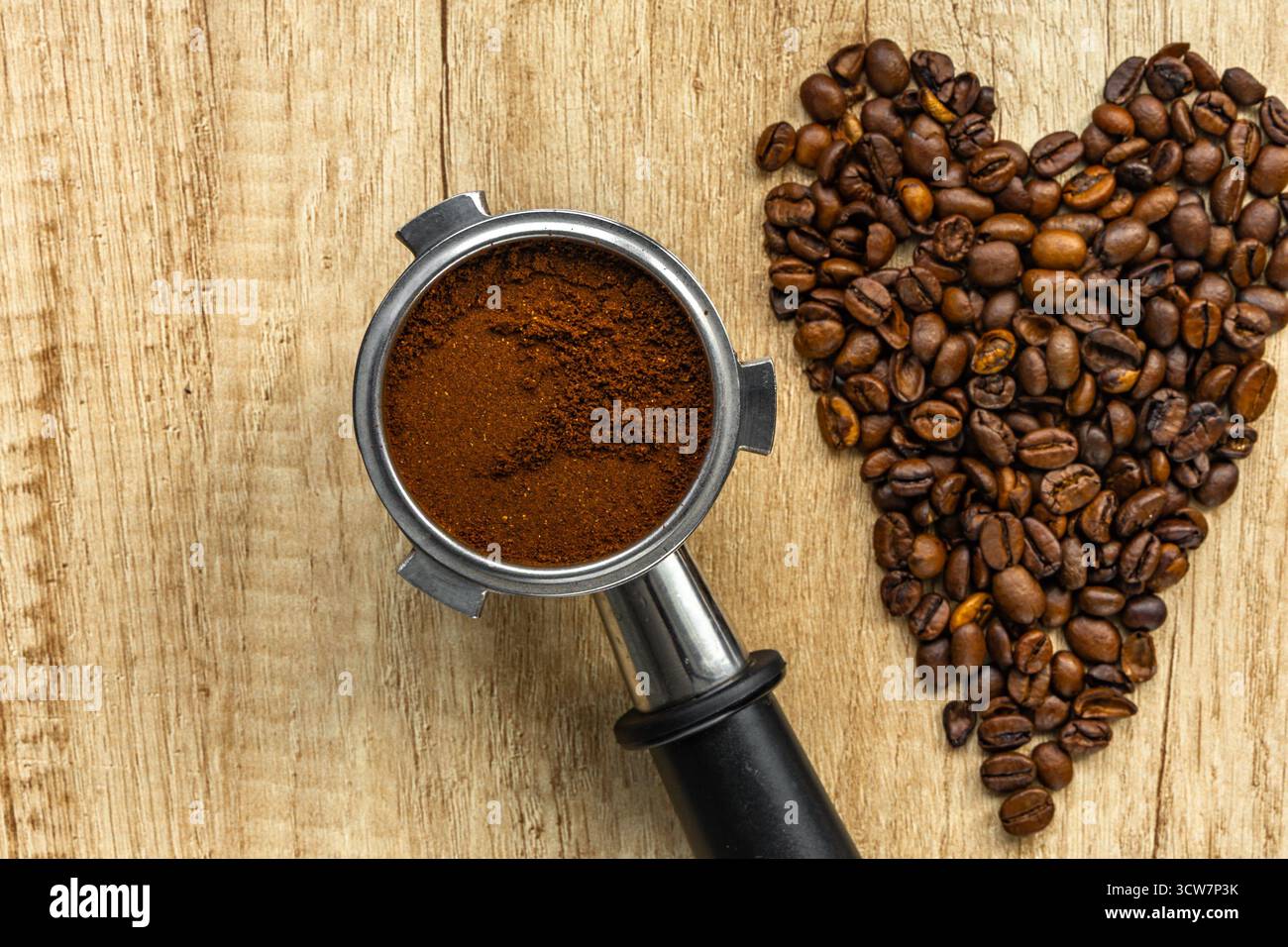 Vista dall'alto di una tazza di caffè con chicchi di caffè a forma di cuore su un tavolo di legno. Simbolo dell'amore per il caffè, la colazione e le accoglienti vibrazioni mattutine. Foto Stock