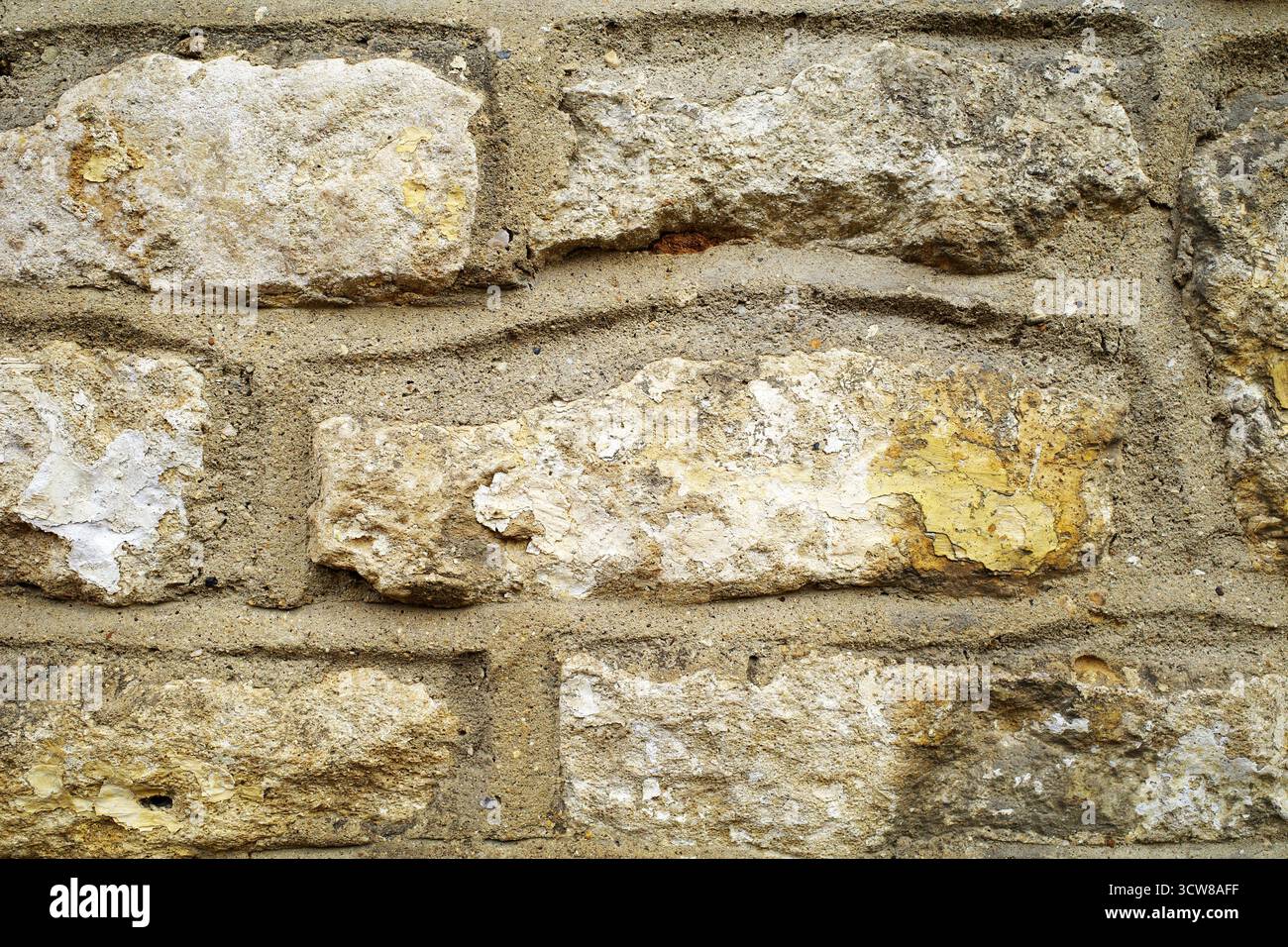 Pareti di pietra grezza nelle Cotswolds, Inghilterra, con blocchi di arenaria di forma irregolare. Varie sfumature di beige, crema e giallo chiaro creano Foto Stock