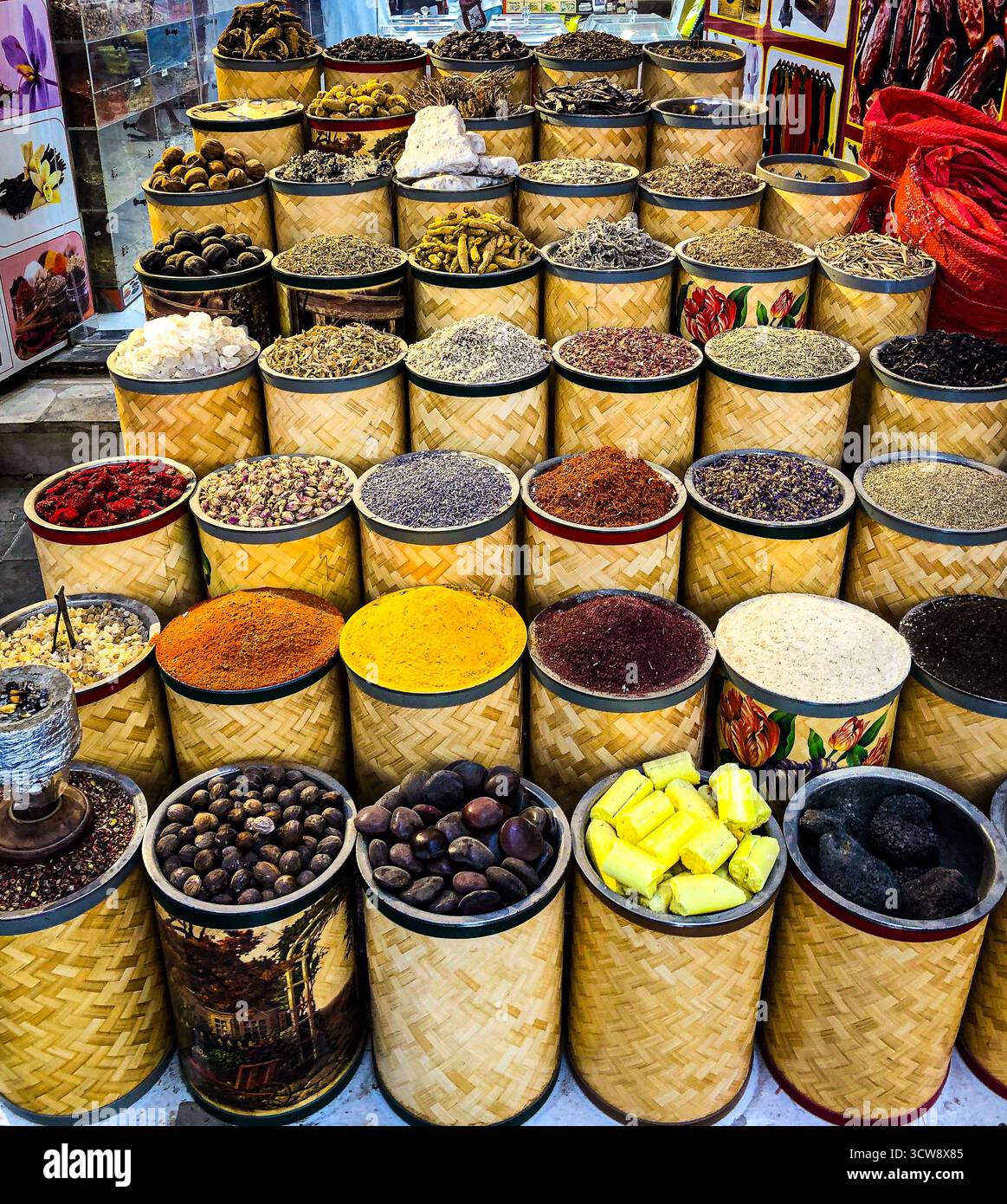 Colorata esposizione di spezie, erbe aromatiche e ingredienti naturali disposti in cesti di bambù intrecciati in un mercato tradizionale. Foto Stock