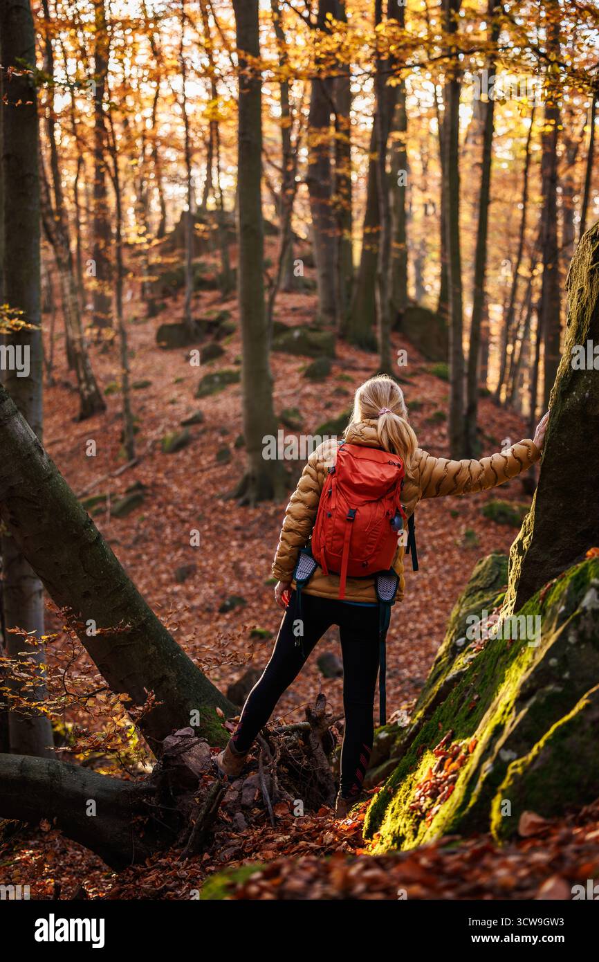 Avventura nella natura. Donna che fa trekking nella foresta autunnale. Escursionista donna con zaino rosso che fa trekking nella natura selvaggia Foto Stock