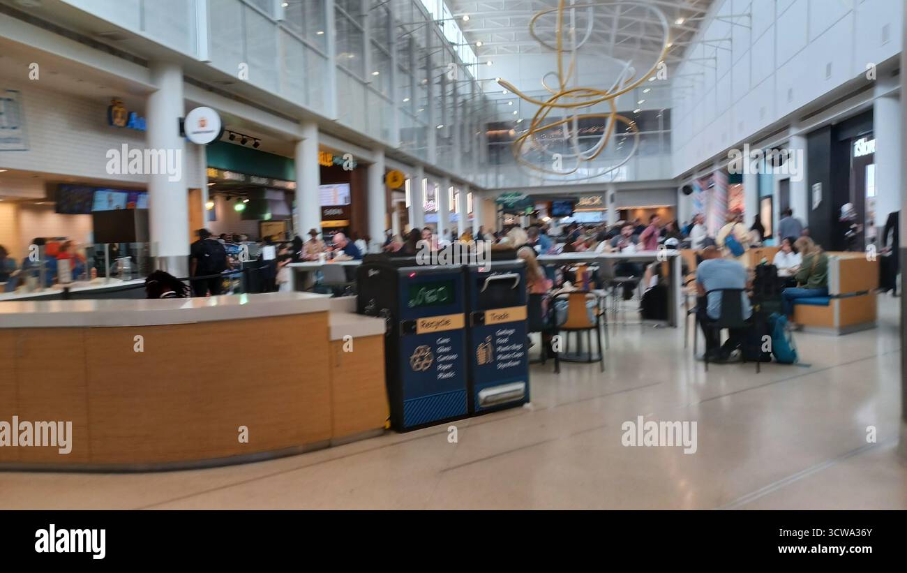 Charlotte, North Carolina, USA, 10 ottobre 2025: Le persone con bagagli attraversano un atrio luminoso e spazioso all'Aeroporto Internazionale Douglas di Charlotte. Foto Stock