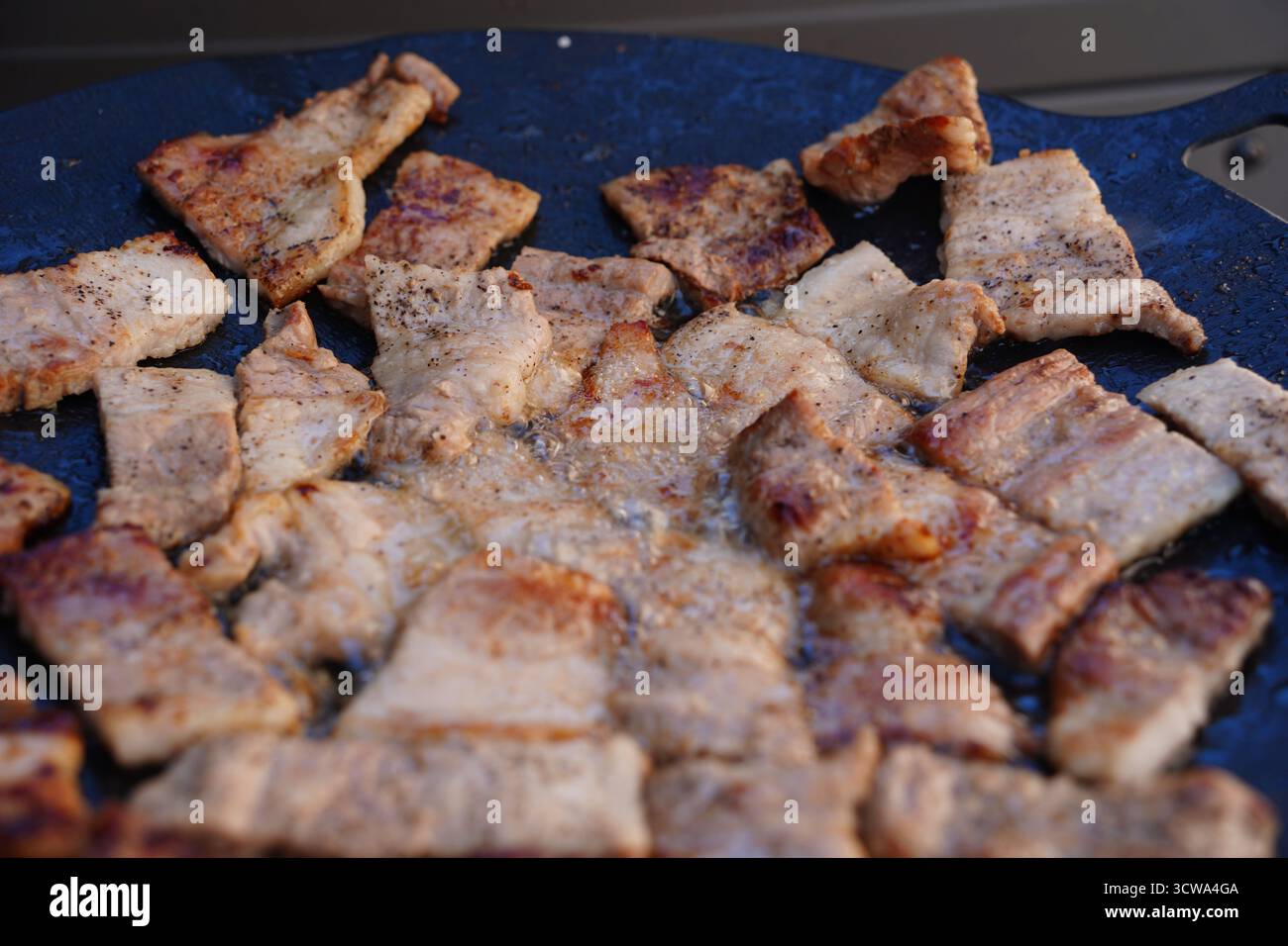 Sfrigolante pancetta di maiale coreana (Samgyeopsal) su una piastra calda Foto Stock