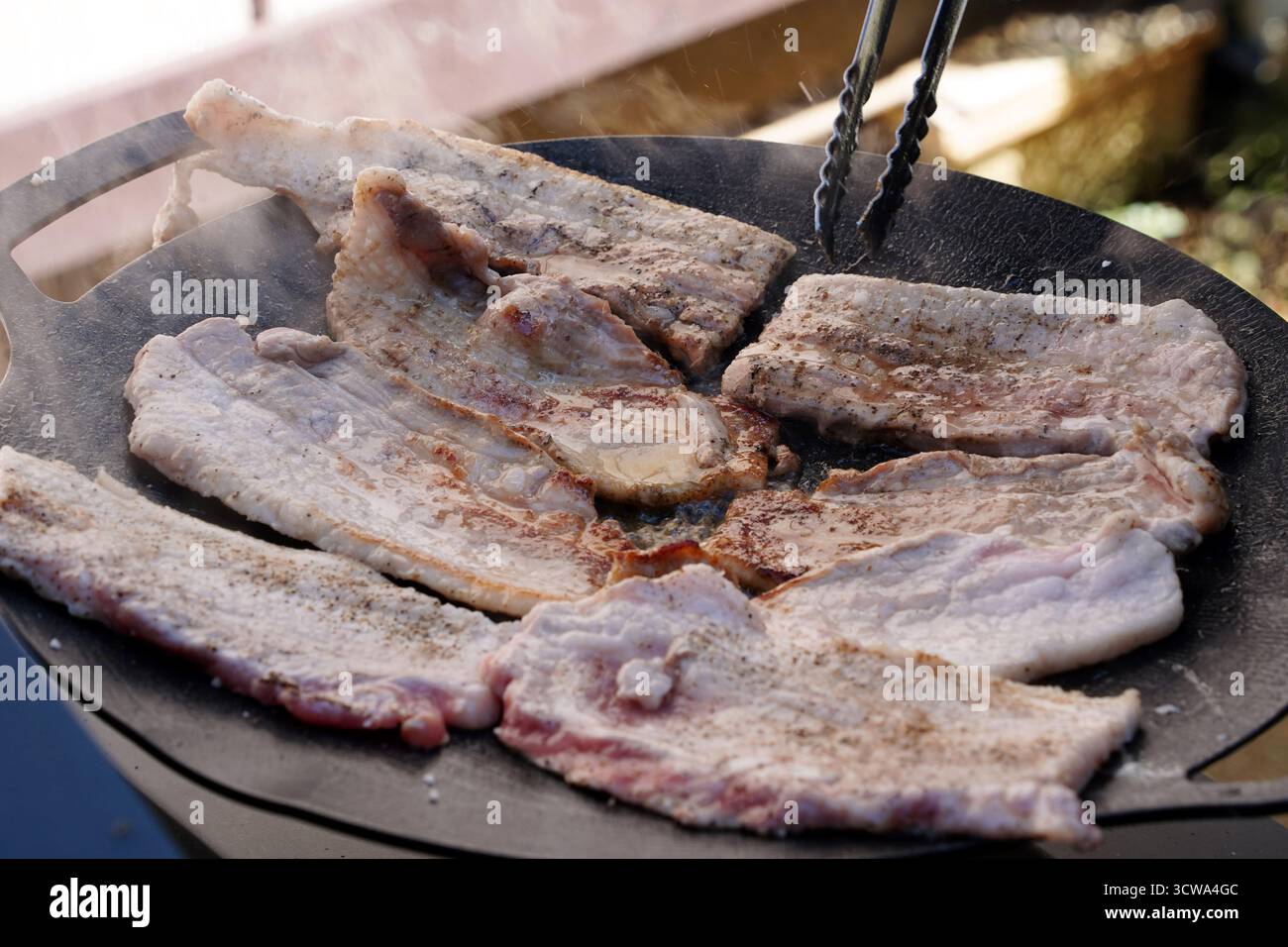 Sfrigolante pancetta di maiale coreana (Samgyeopsal) su una piastra calda Foto Stock