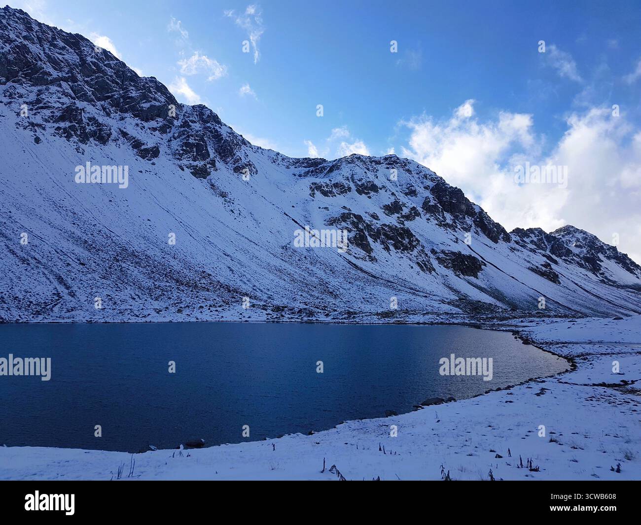 Scenario invernale sul passo Flüela con piste innevate e lago ghiacciato, cielo blu e nuvole bianche, Engadina, Svizzera Foto Stock