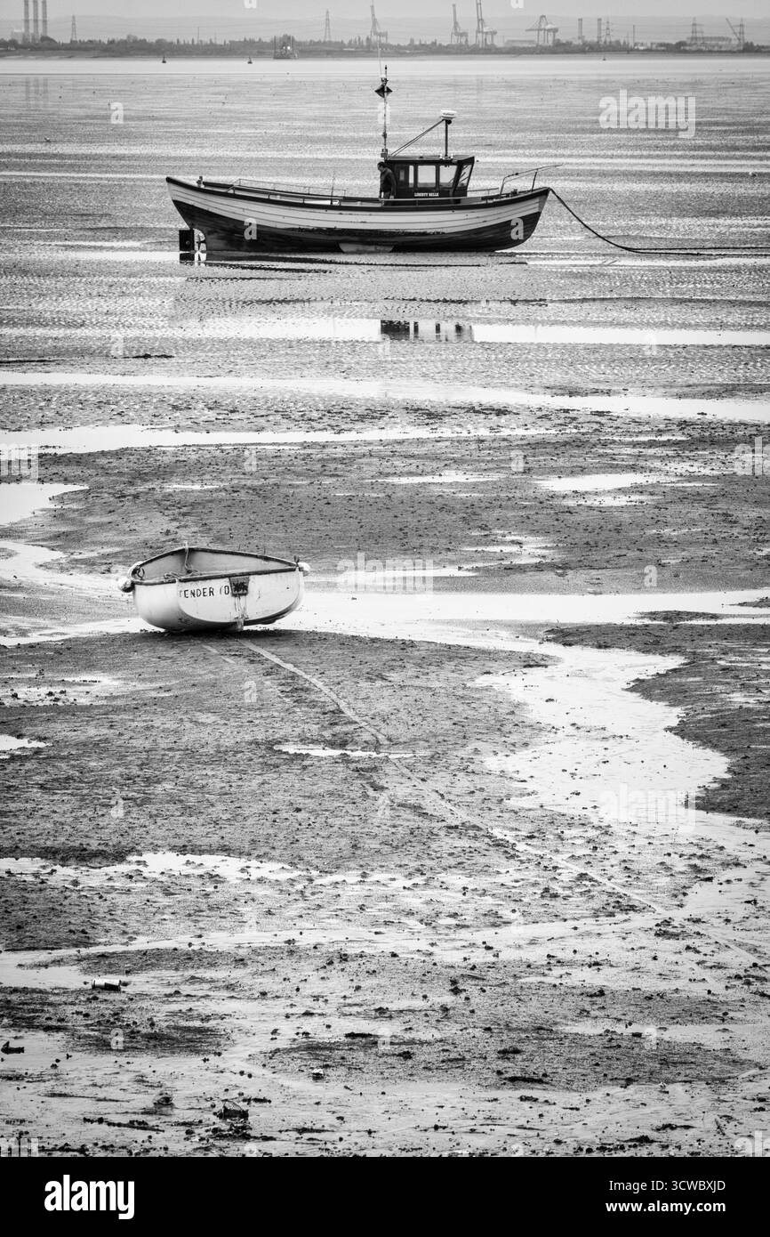 Barca e Dinghy a riposo sulle distese fangose al largo di Thorpe Bay in una mattinata di ottobre molto noiosa Foto Stock